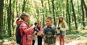 New places. Kids in green forest at summer daytime together